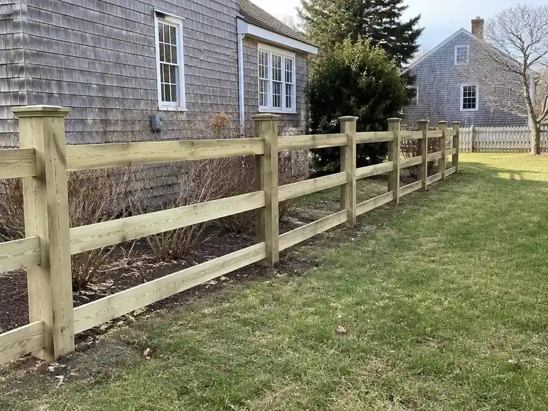 New wood post and rail fence installed beside a Cape house in Massachusetts